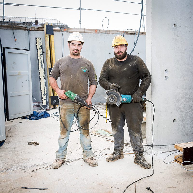 Portrait de deux maçons avec leurs outils sur un chantier de construction d'un batiment d'habitation par une photographe d'architecture